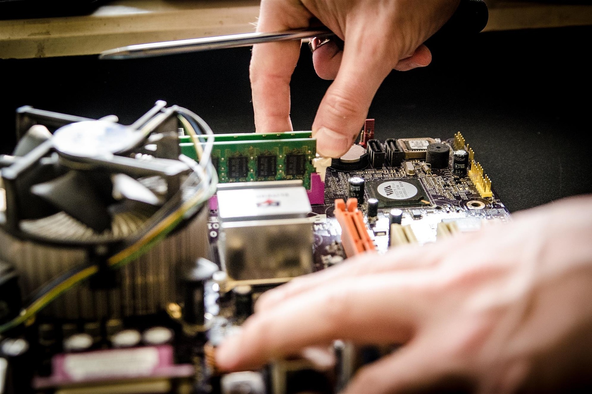 Techniker repariert einen Computer und tauscht den Arbeitsspeicher auf dem Mainboard aus.